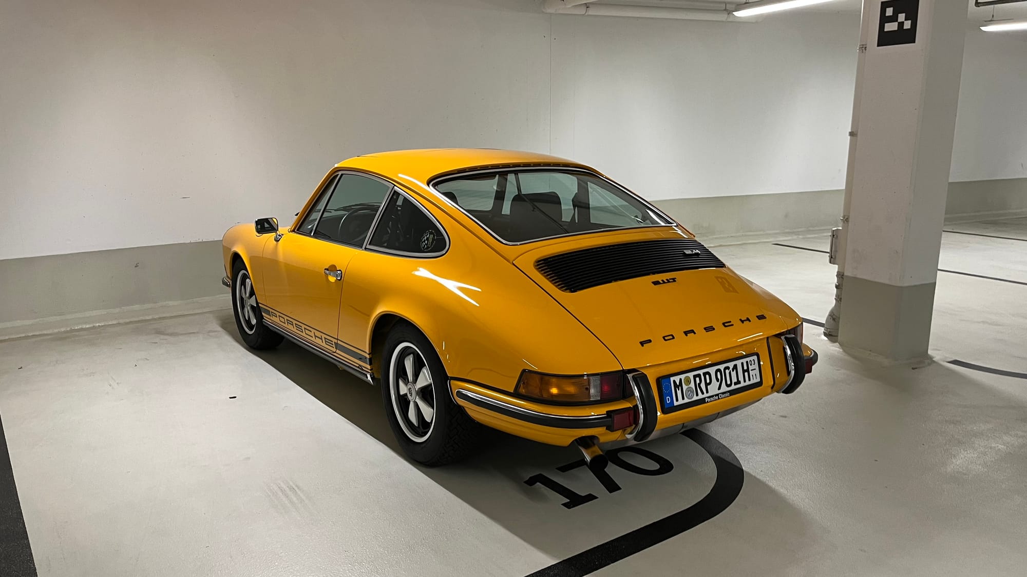 A classic 911 in Bahama Yellow parked in the museum underground